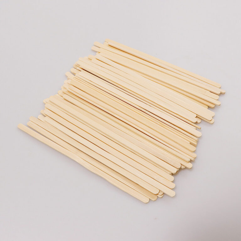 Pile of round-ended disposable bamboo coffee stirrers on a light background